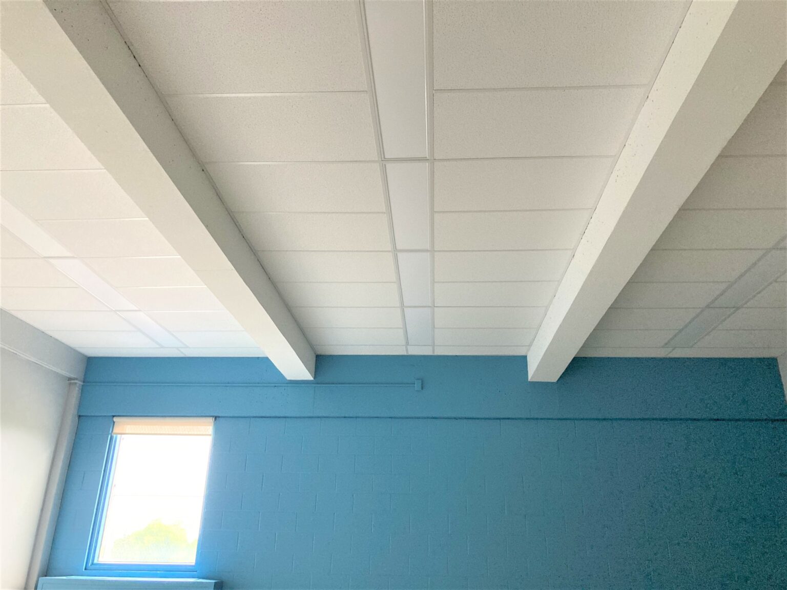 Plafond blanc avec poutres apparentes.